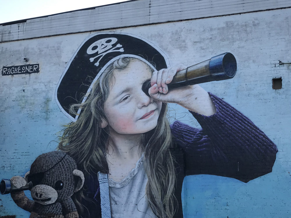 Street art of girl with pirate hat and telescope